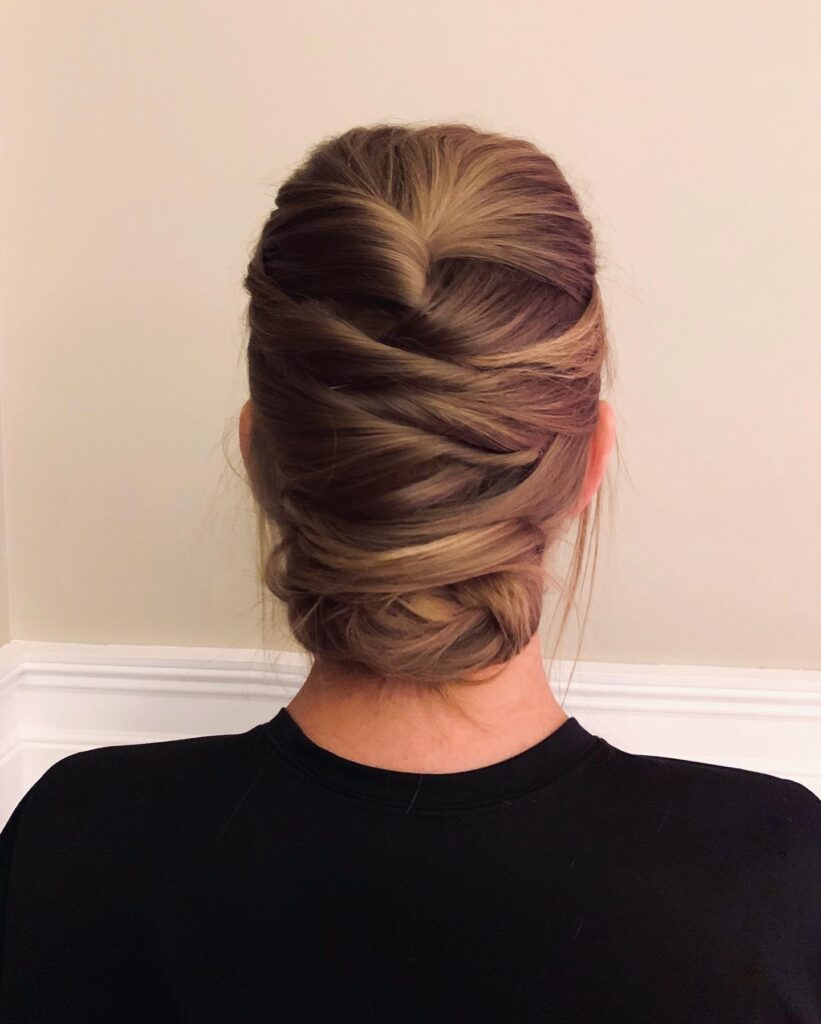 A mousy brown low updo featuring a series of overlapping criss-cross sections is seen from behind.