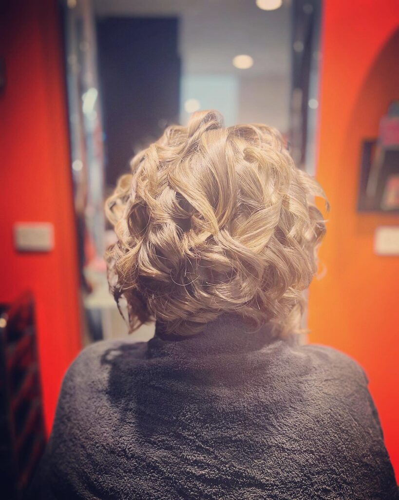 A back view of a woman with an ash brown bob featuring glossy and well-defined ringlets.