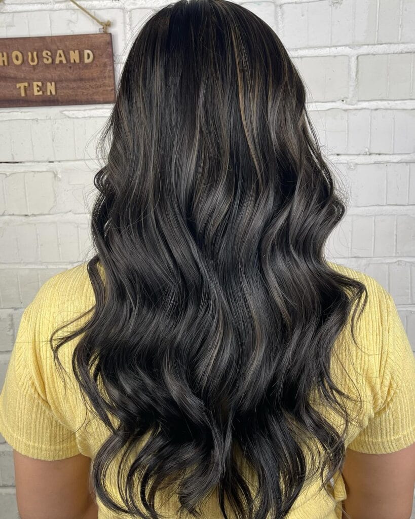 Long dark hair with sleek defined waves and a smooth shiny finish.
