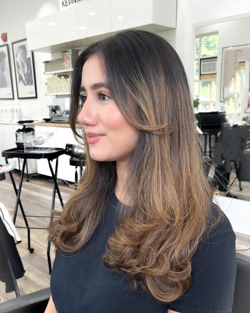 Long brunette hair styled in a bouncy blowout with soft layers and rounded ends.