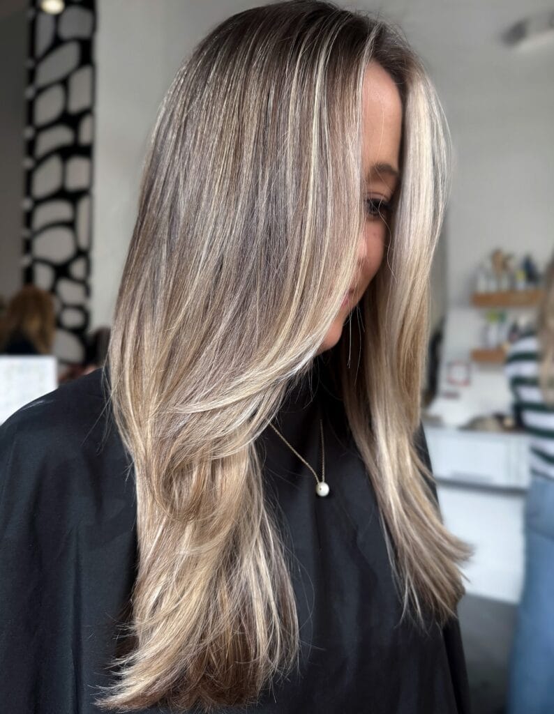 Long ash blonde layered hair with a soft flowing shape and light texture.