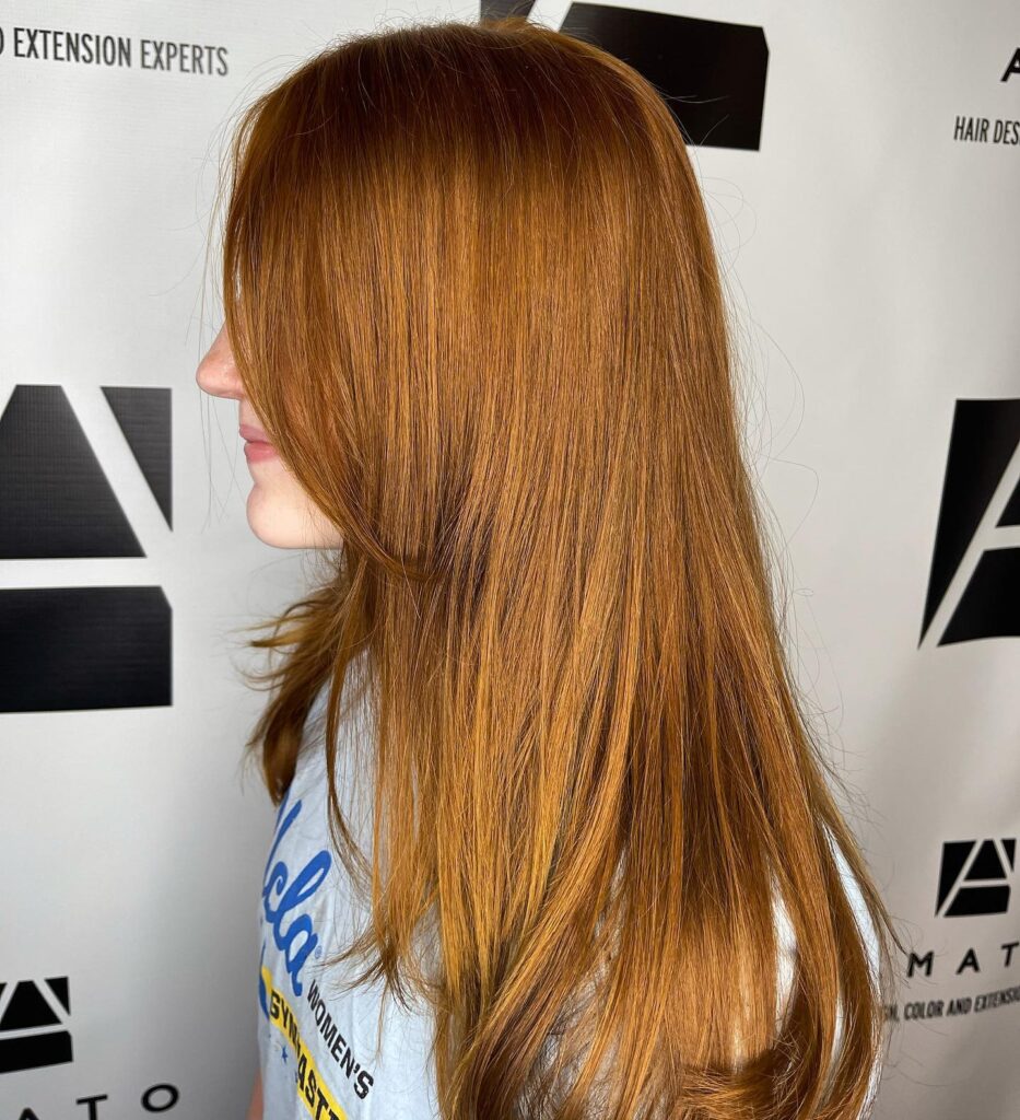 A teenage girl with long straight copper ginger hair featuring face framing layers and a smooth polished finish.