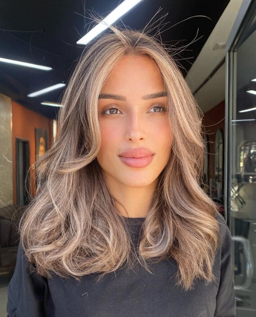 A woman with shoulder length layered hair styled in a soft blowout with natural movement.
