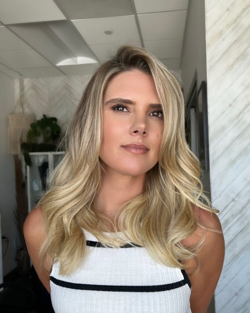 A woman with medium length blonde hair styled in a soft blowout with loose volume.