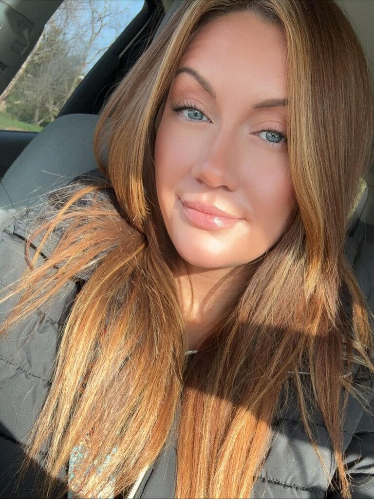 A woman with long straight hair styled with a center part and natural shine.