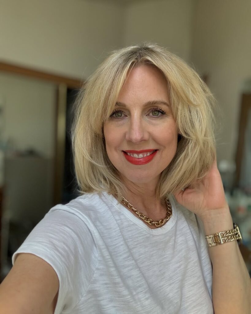 Chin-length blonde bob with soft curtain bangs and a smooth finish.