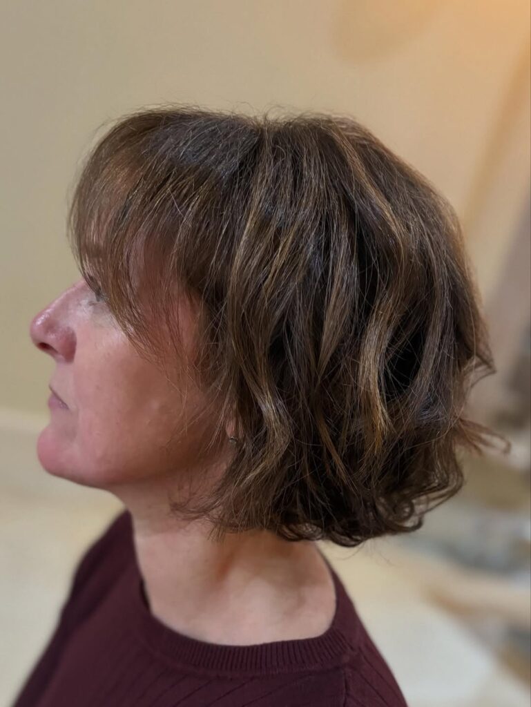 Short layered brunette bob with soft waves and side swept bangs.