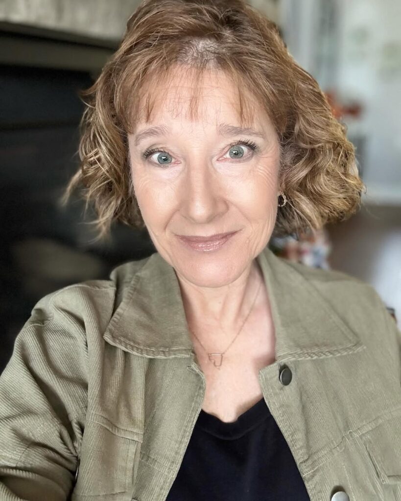Chin-length curly auburn bob with light wispy bangs and soft texture.