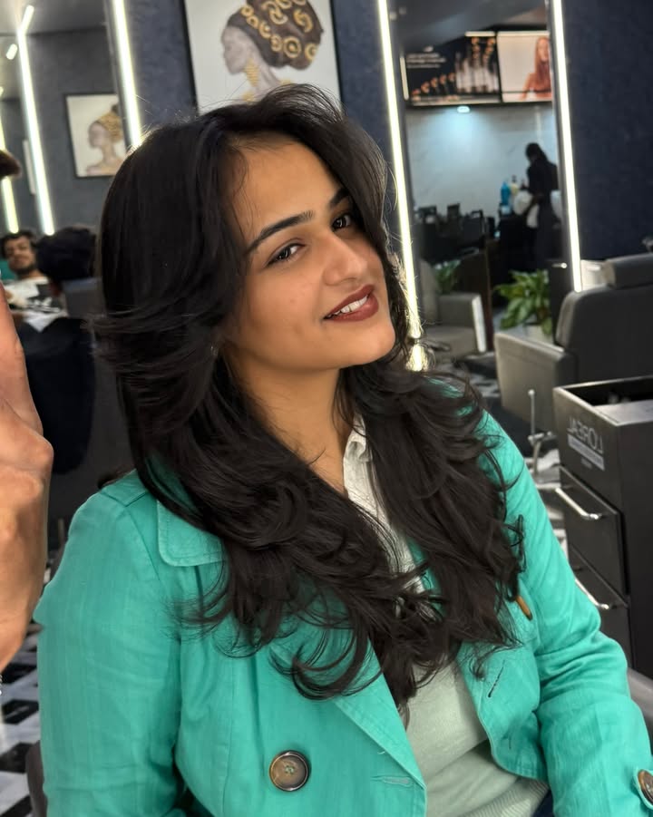 Long layered hair with curtain bangs and soft voluminous waves.