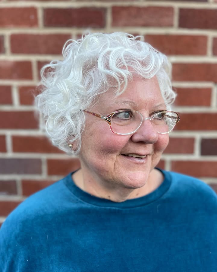 Short curly white hair with soft airy bangs and natural volume.