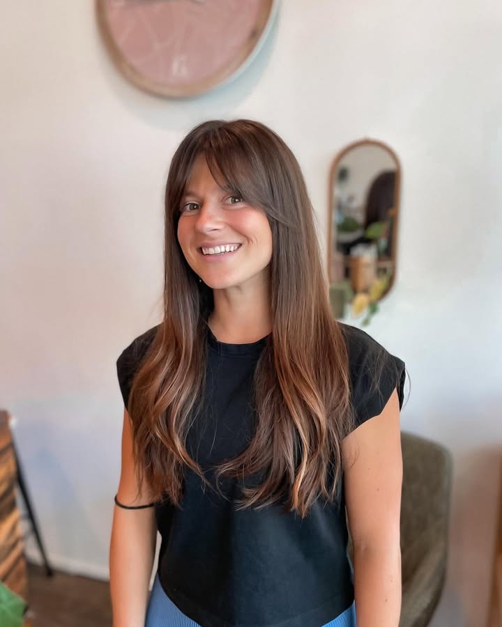 Long straight layered hair with light curtain bangs and soft movement.
