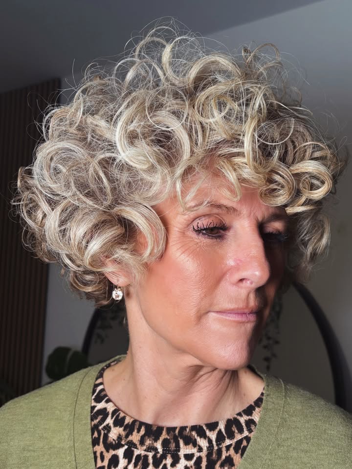 Short curly blonde hair with soft volumizing bangs and bouncy texture.