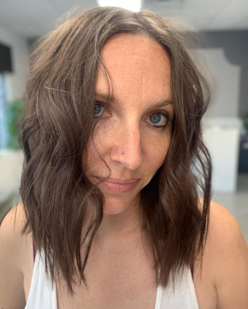 A middle-aged woman with a shoulder-length, loose-wave brunette bob haircut and light freckles.