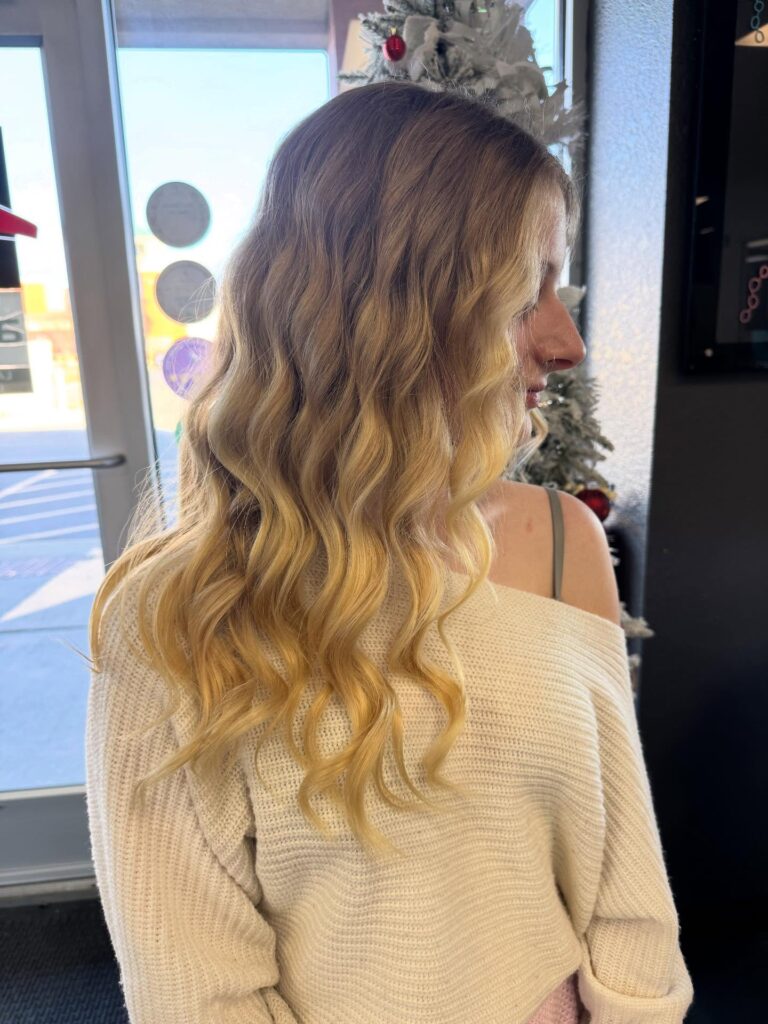 A woman with medium length honey blonde hair styled in tight uniform crimped waves.