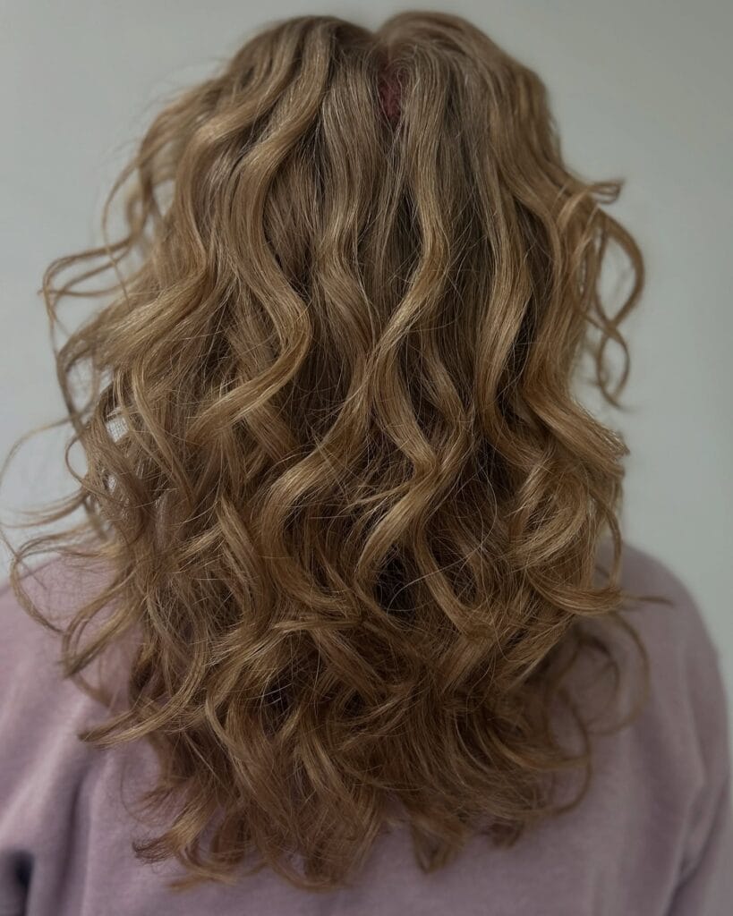 Long brown wavy hair with voluminous layers and full shape.