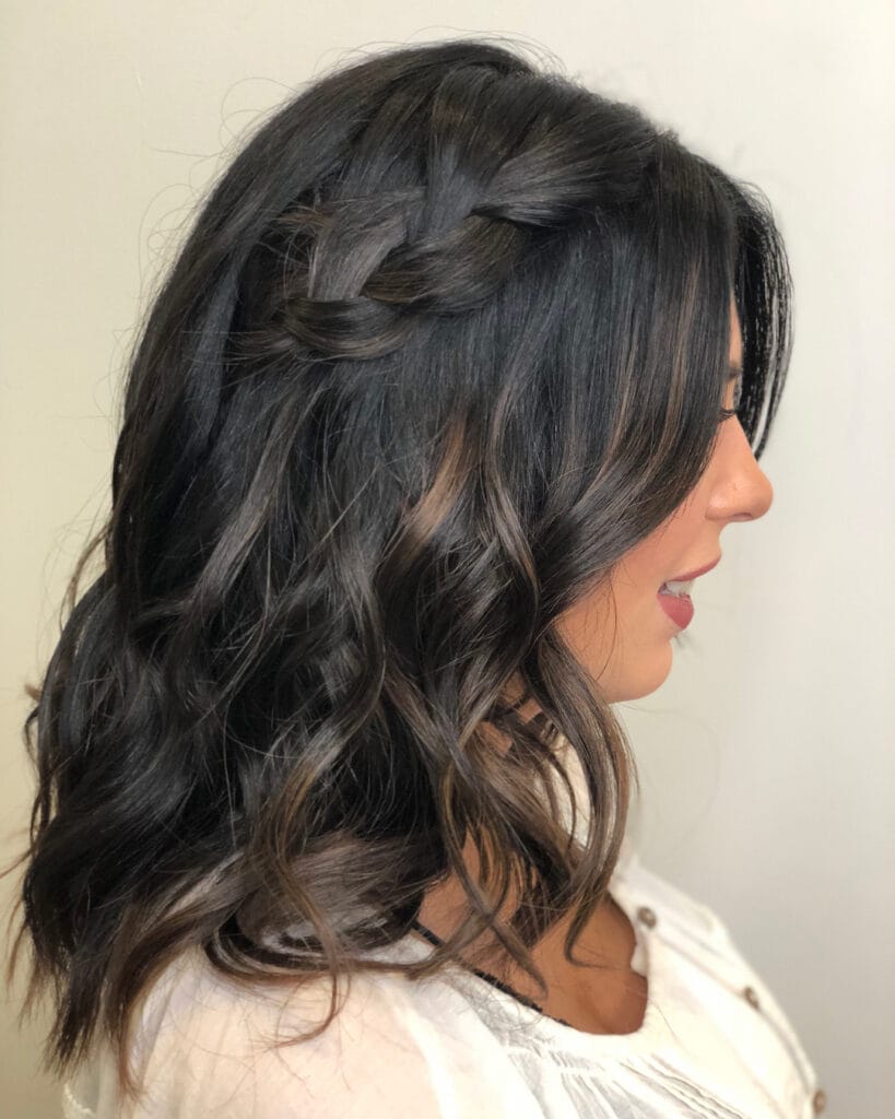 Shoulder-length dark wavy hair with face-framing layers and soft waves.
