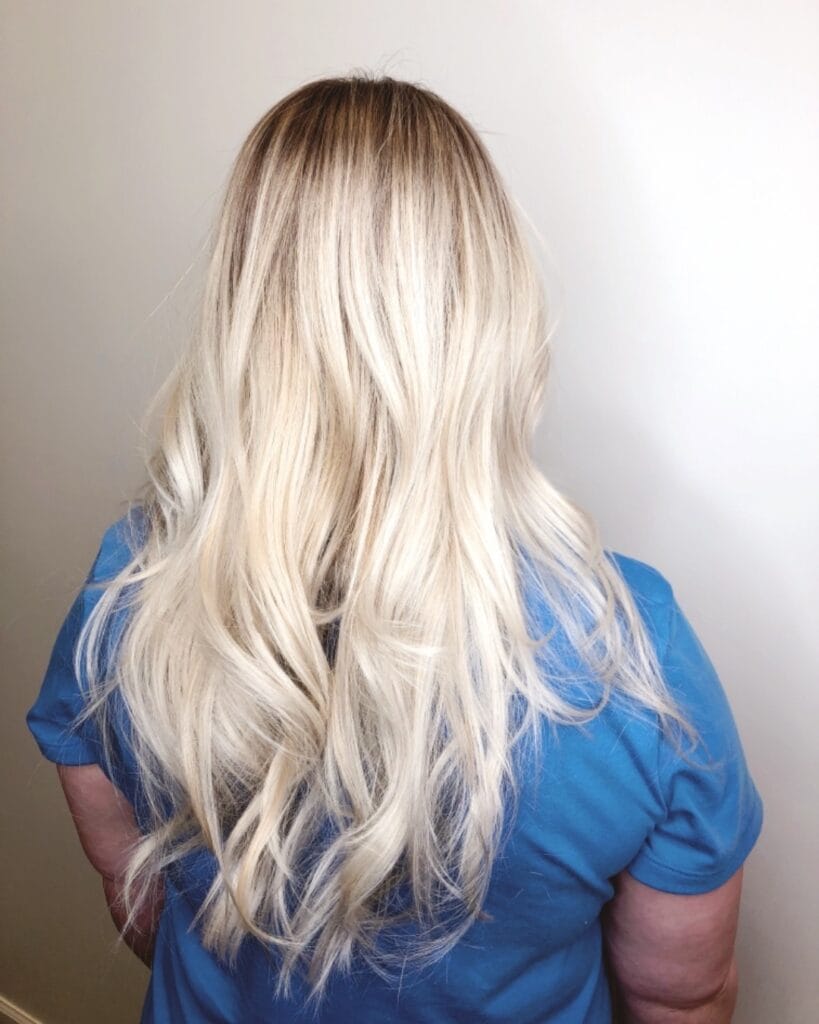 Long blonde wavy hair with soft seamless layers and smooth flow.