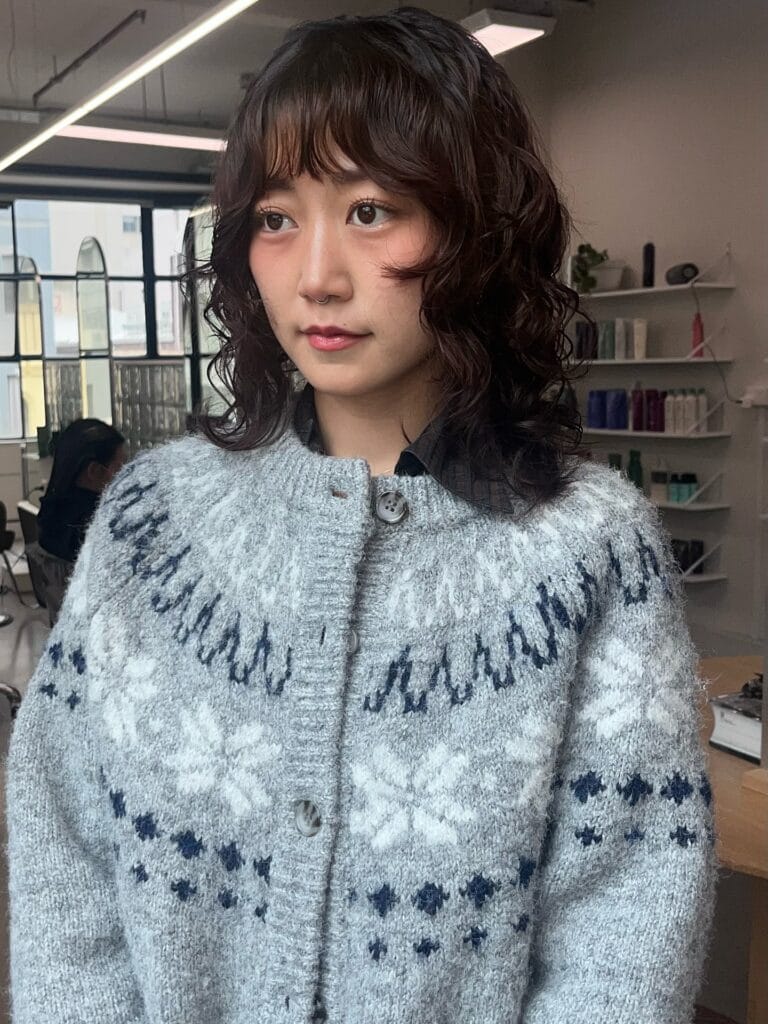 Medium-length wavy hair with shaggy layers and a soft fringe.