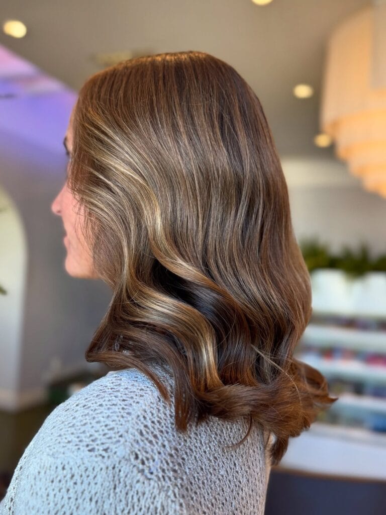 Shoulder-length brunette wavy hair with soft layers and a polished finish.