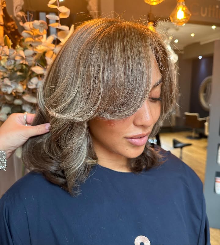 Shoulder length layered blonde hair with volume and side swept bangs.