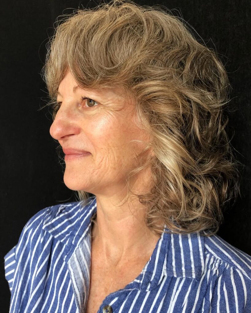 Medium length layered blonde hair with feathered bangs and soft volume.