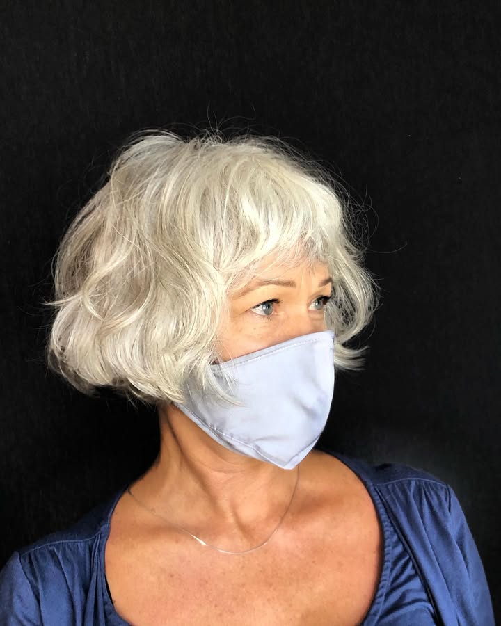 Short curly gray bob with soft natural bangs and a rounded shape.