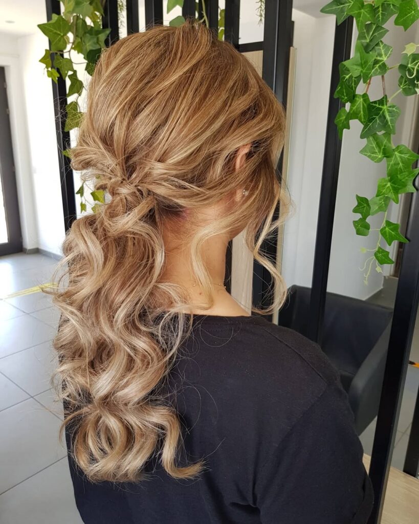 Blonde wavy hair styled in a twisted half up look with loose waves flowing down.