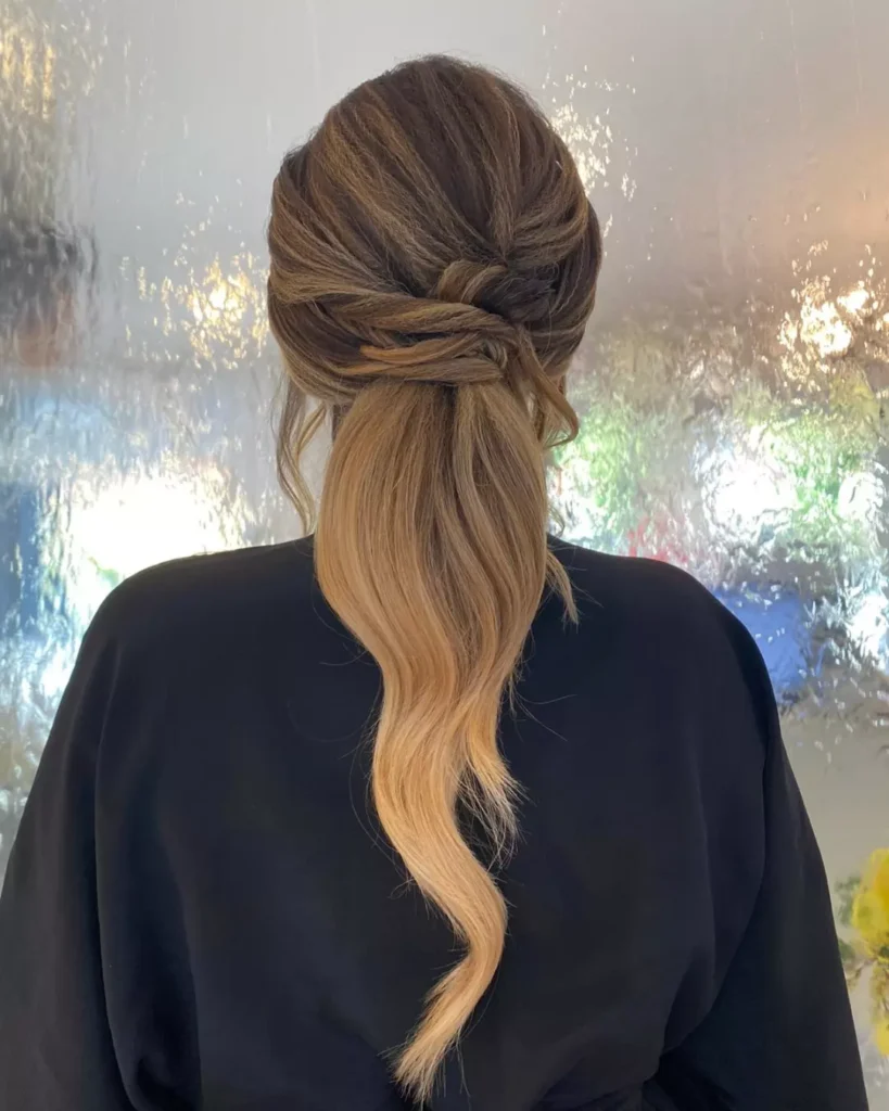 Half up hairstyle with twisted sections and soft waves flowing down the back.