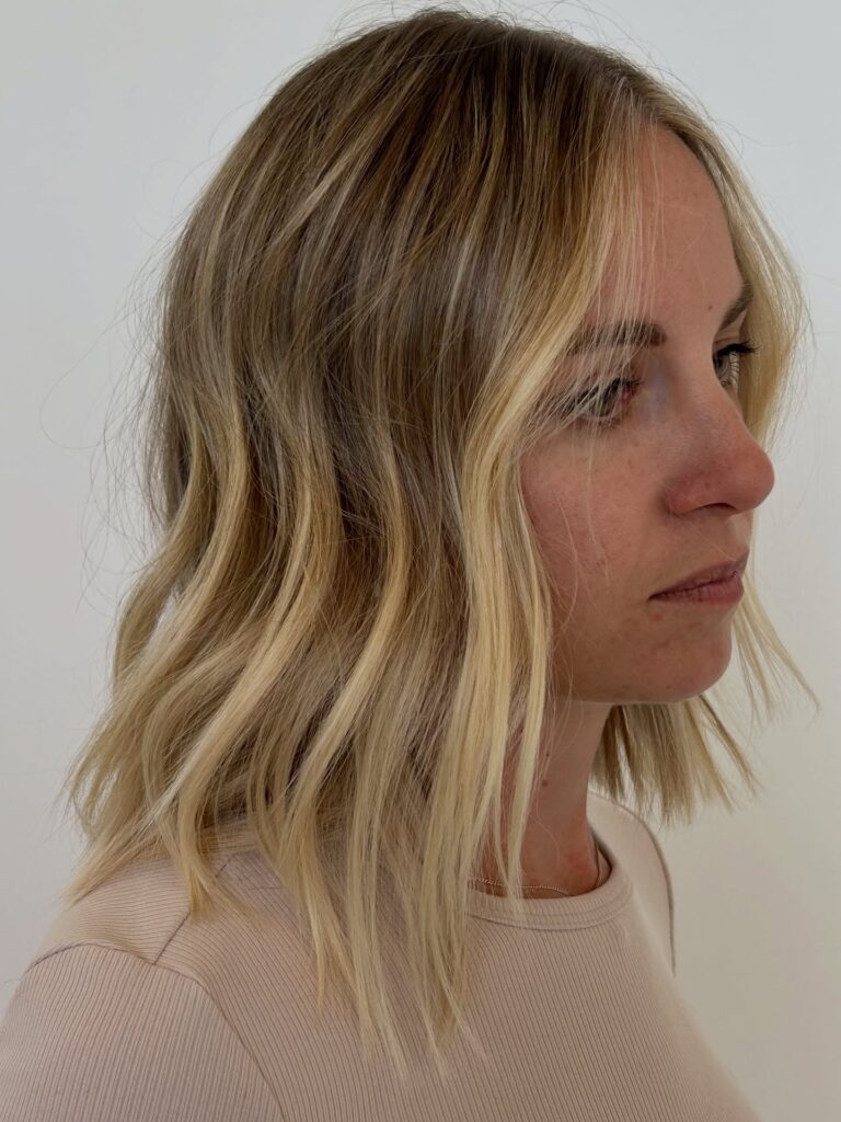 Blunt lob with soft beachy waves and blonde balayage for a natural textured look.