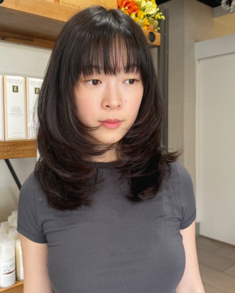 Shoulder length dark brown hair with a full fringe and softly layered ends.