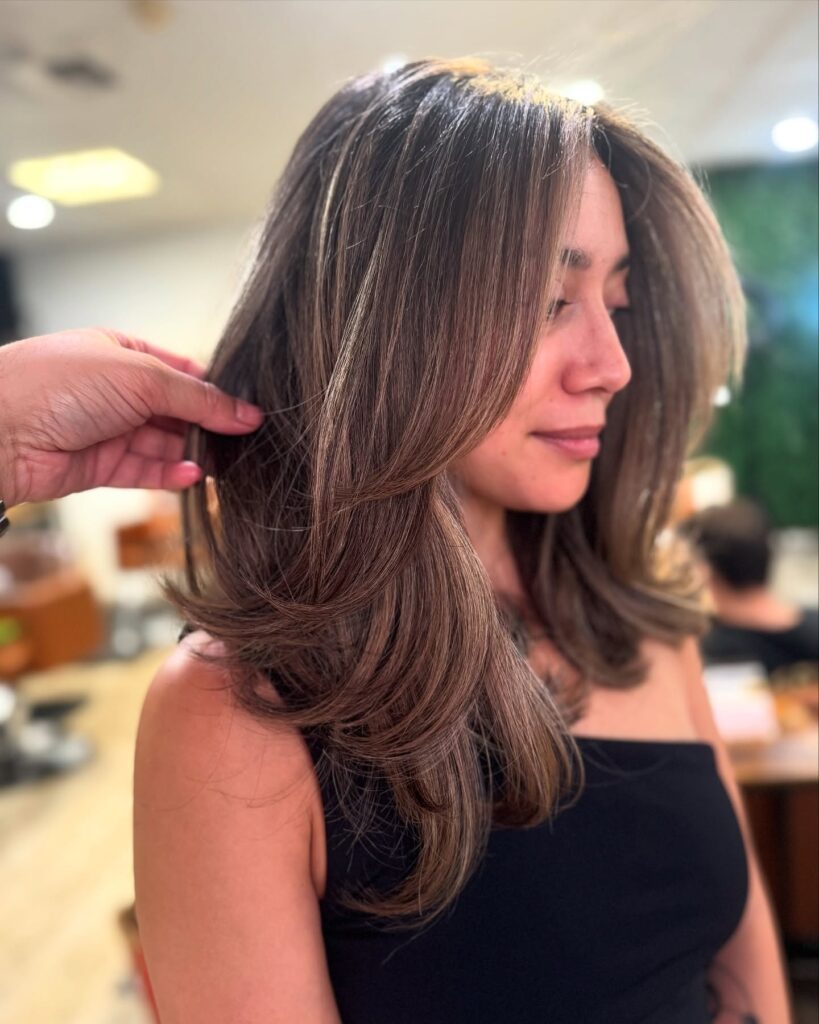 A woman with a short layered haircut featuring bouncy volume and soft rounded layers.