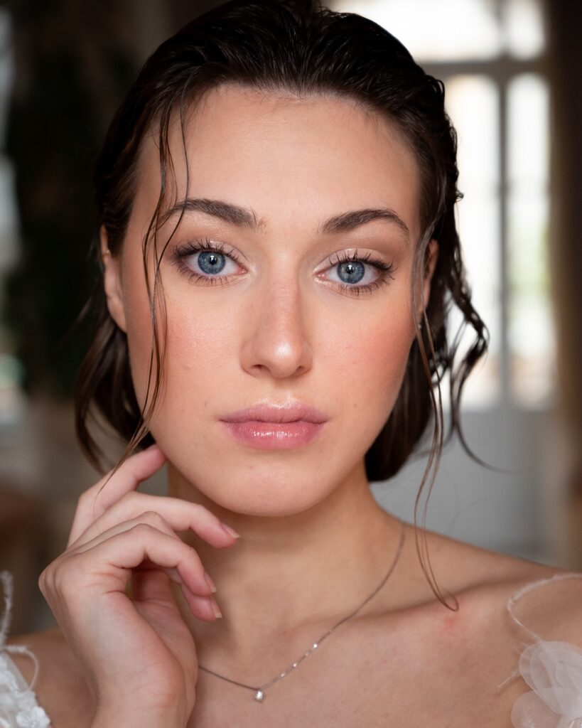 A woman with short hair styled back with a soft slicked finish and natural texture.