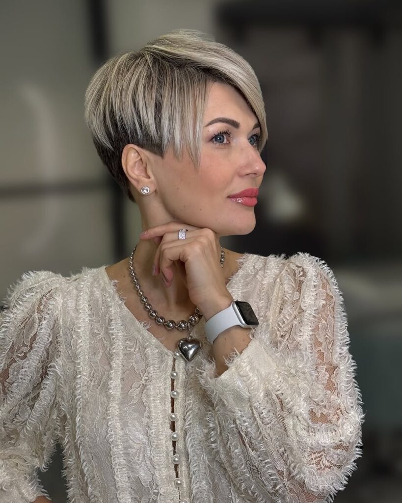 A woman with a sleek silver pixie haircut with tapered sides and longer top layers.