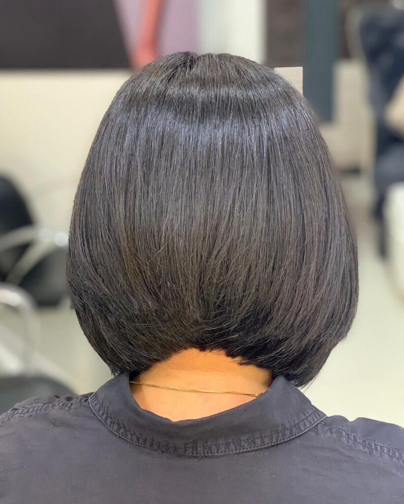 A woman with a short textured brunette pixie haircut with soft fringe and natural layers.