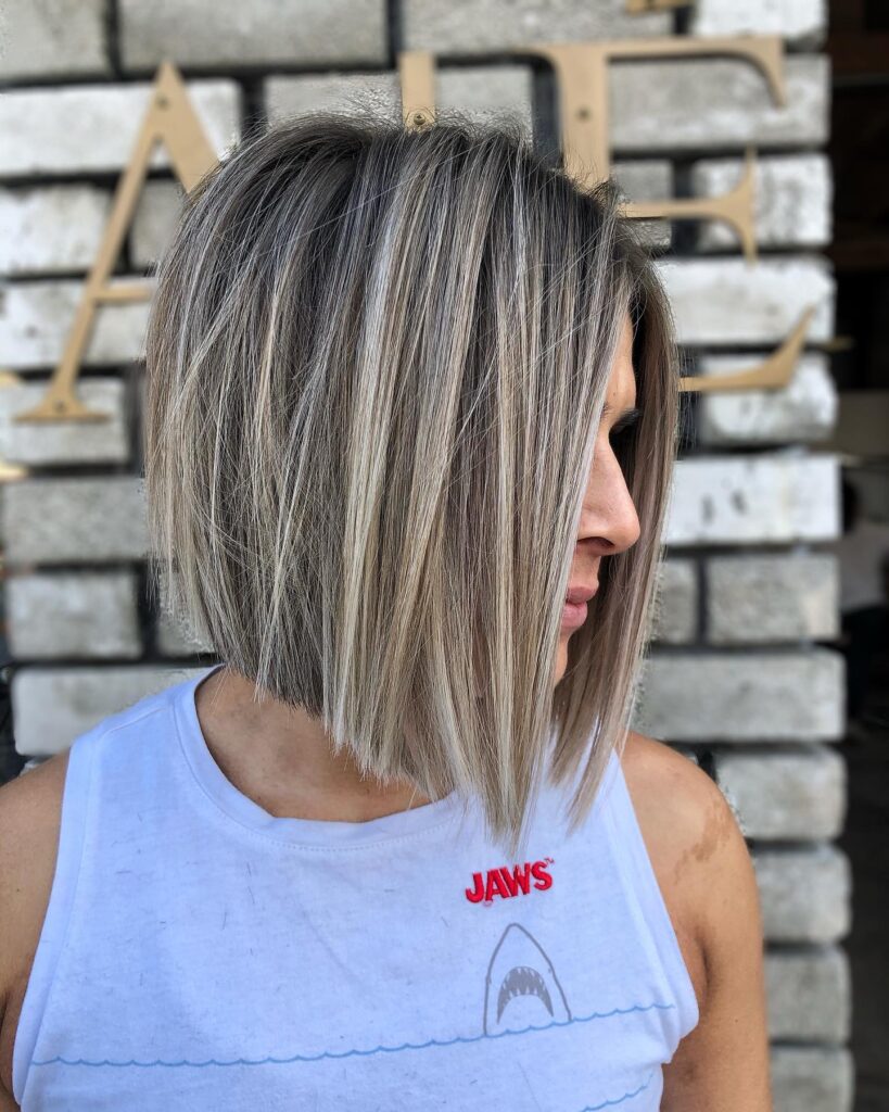 A woman with a sleek angled blonde bob haircut with longer front pieces and a sharp finish.