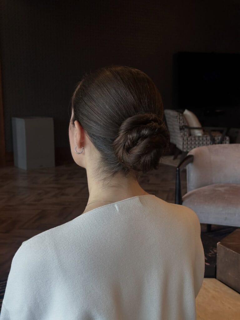 Brown hair styled into a low twisted bun with soft layered texture.