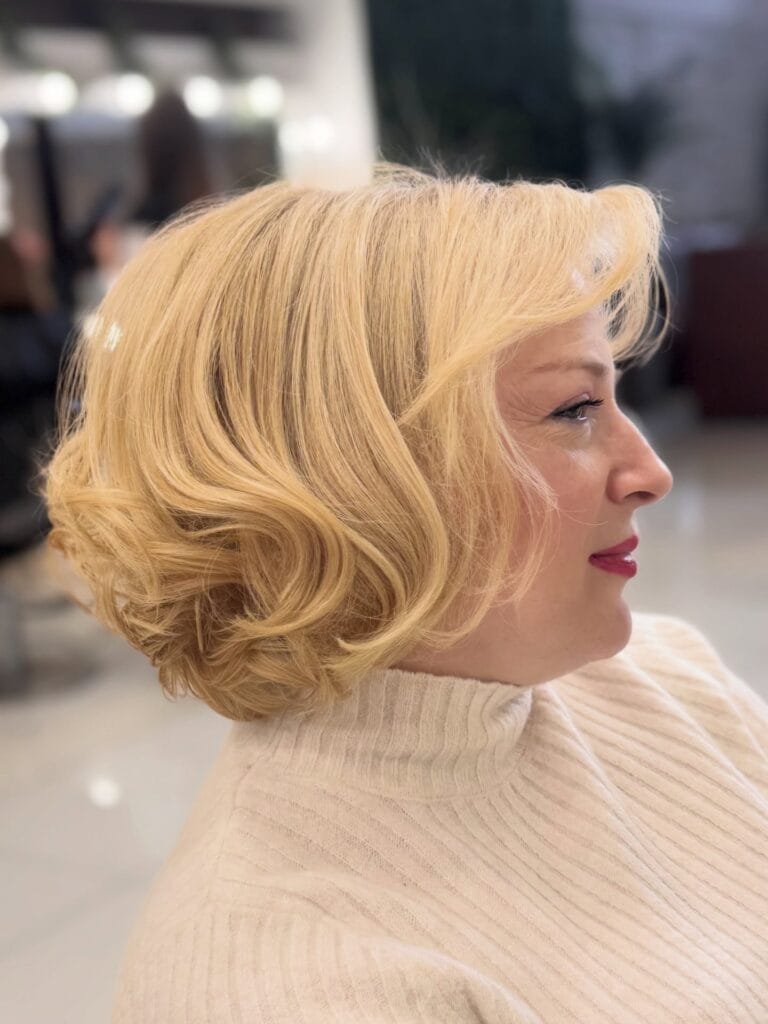Blonde bob haircut styled with soft waves and smooth volume.