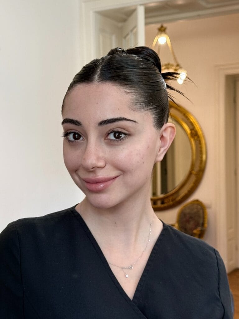 Dark hair styled into a sleek low bun with a center part and smooth finish.