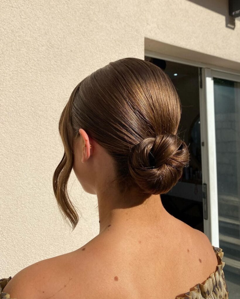 Brown hair styled into a sleek low knot with a soft side sweep.