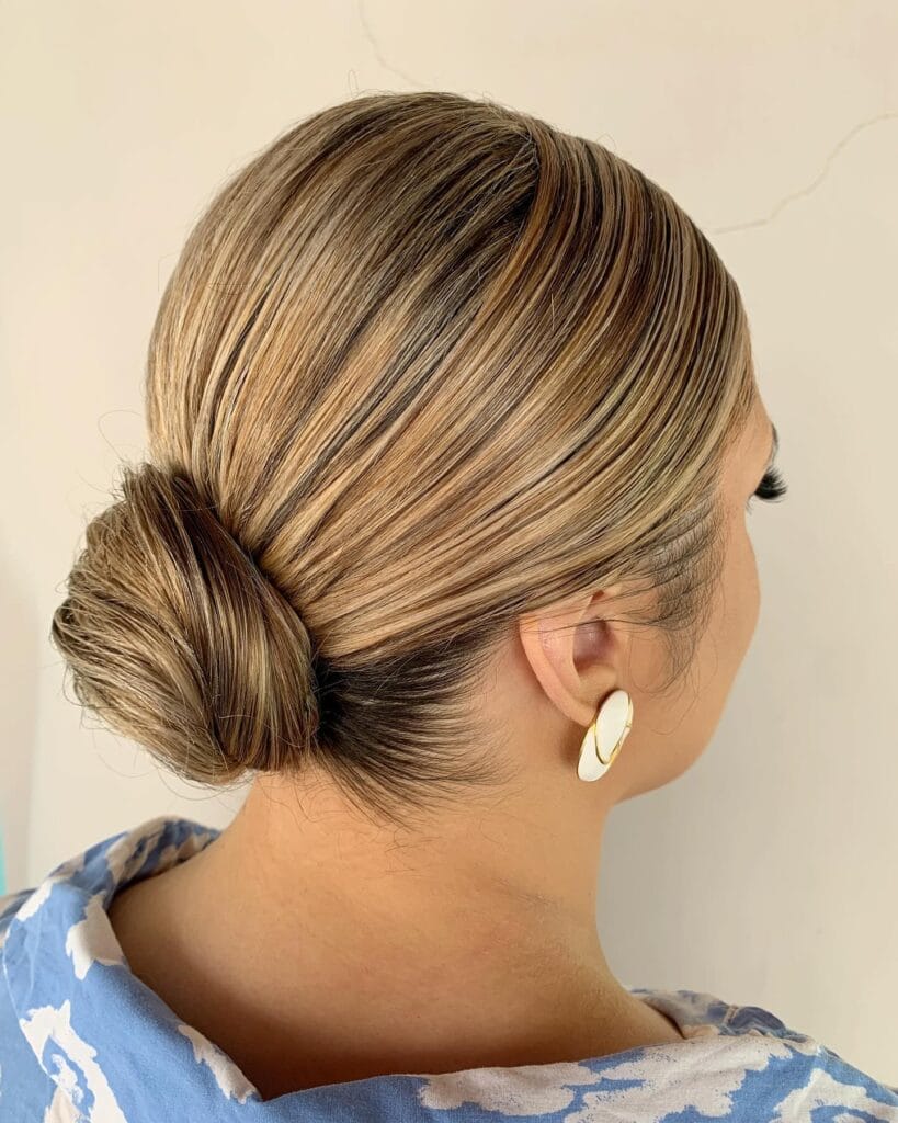 Blonde hair styled into a smooth low bun with soft volume at the nape.