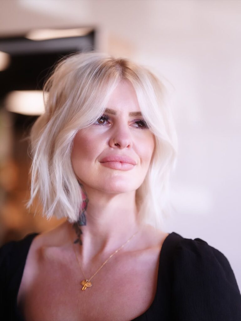 Shoulder length blonde hair with soft layers and airy curtain bangs swept to the sides.