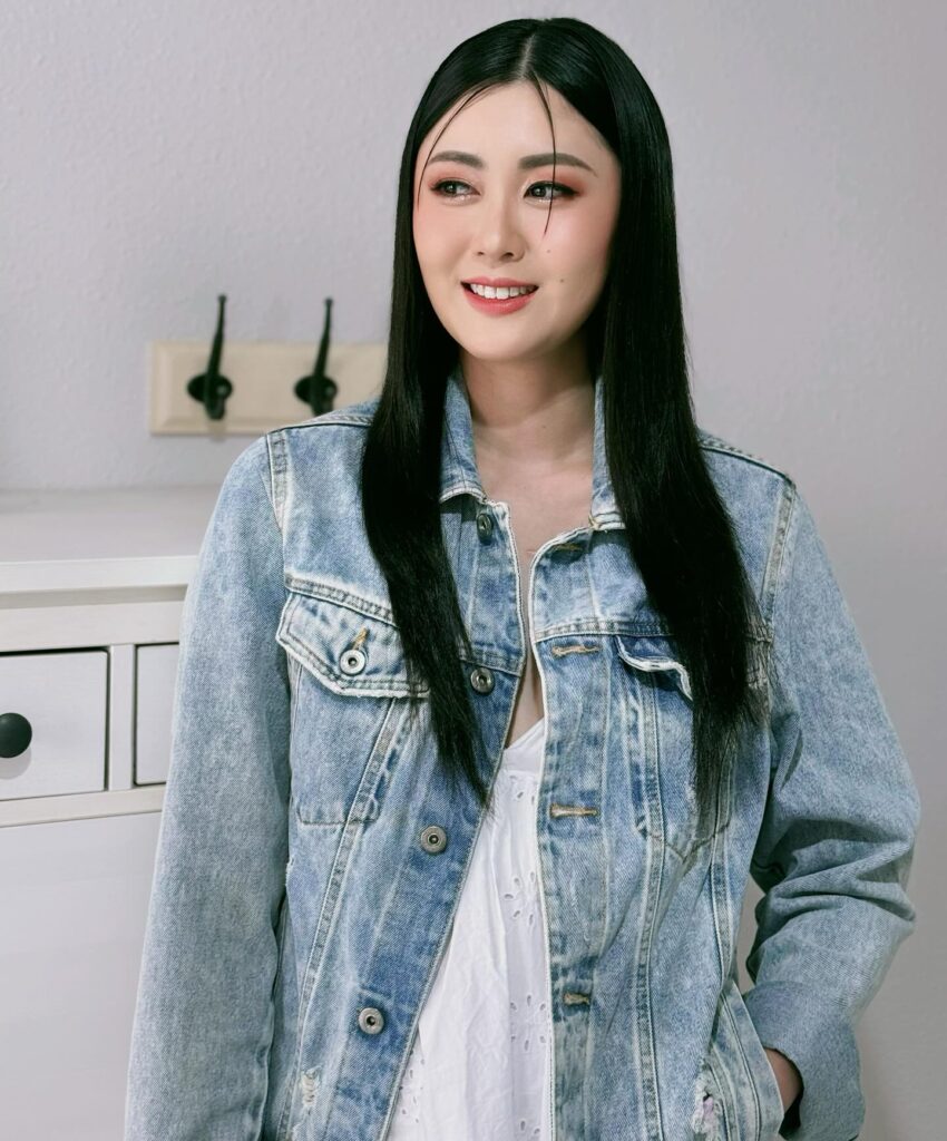 A smiling woman with long, straight black hair parted down the middle and draped over her shoulders.