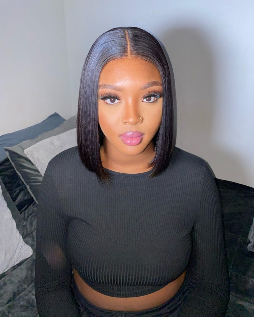 A woman with a sleek, shoulder-length blunt lob in a deep black shade featuring a center part and glossy finish.