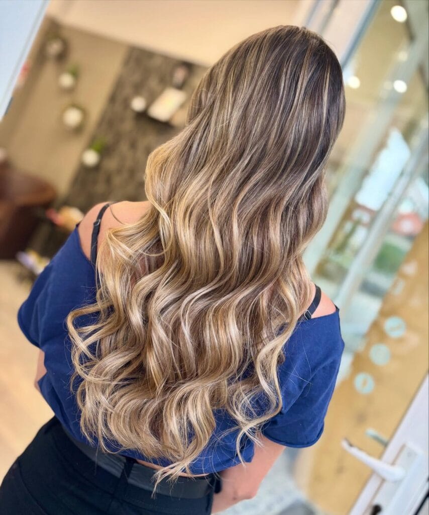 Long blonde balayage hair with soft, flowing waves and natural blend.