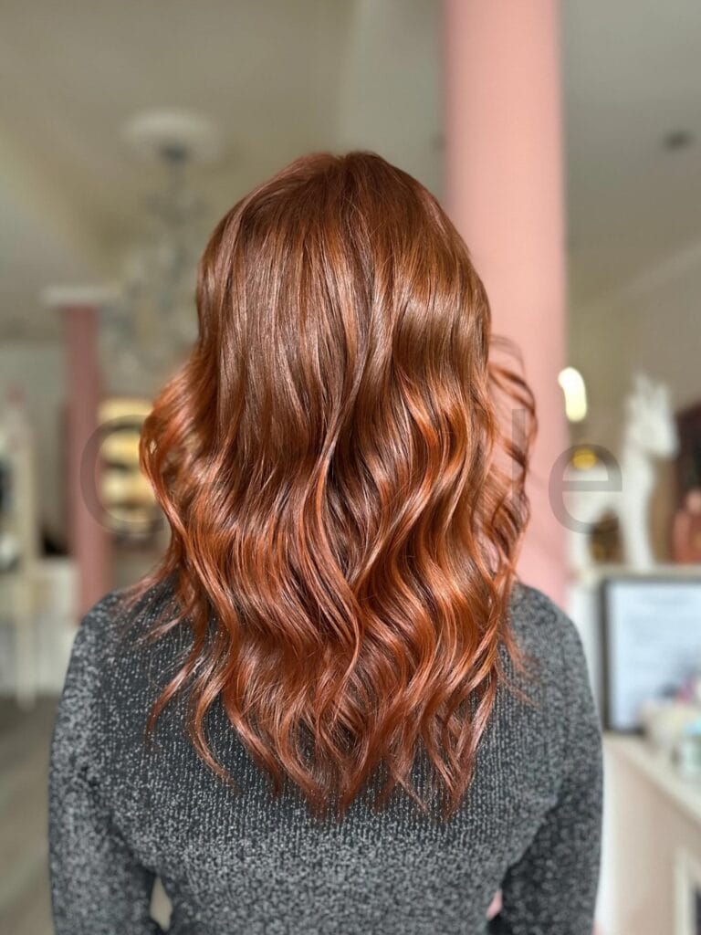 Medium to long copper hair with soft waves and a rich, glossy shine.