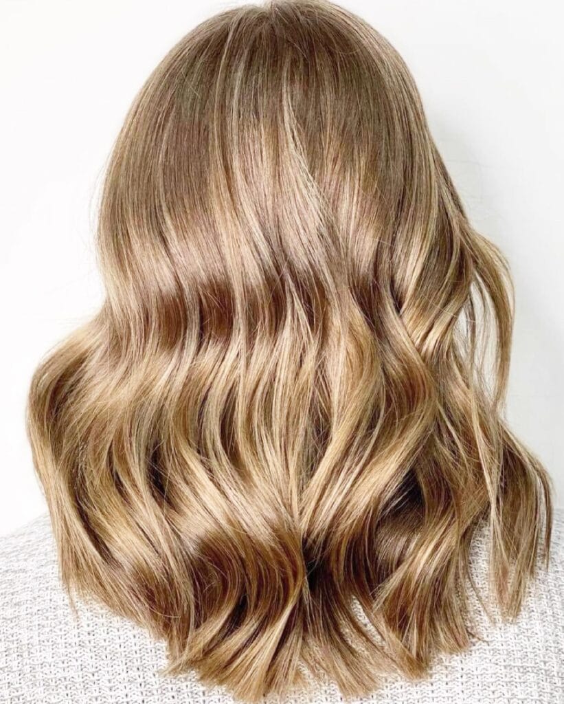 Medium to long blonde hair with soft, natural waves and light texture.