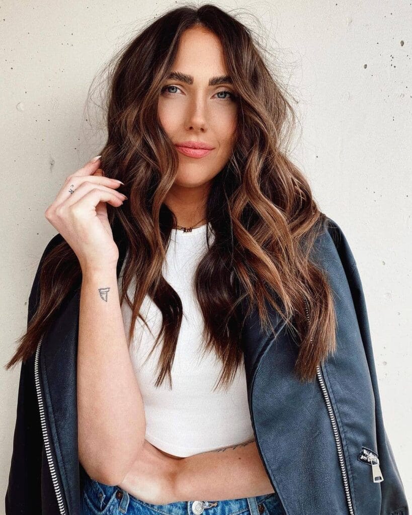 Long brunette hair with soft waves and subtle blended highlights.