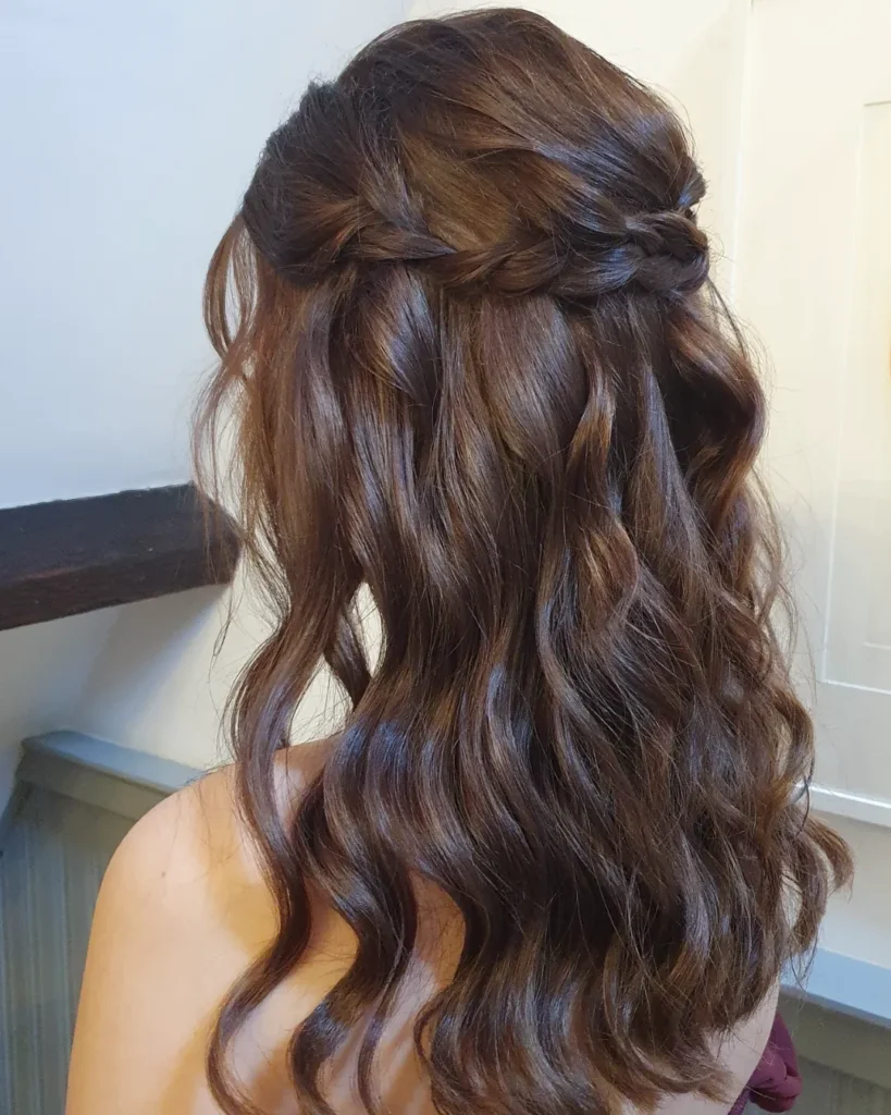 Long layered brunette wavy hair with a subtle braid tucked into the back.