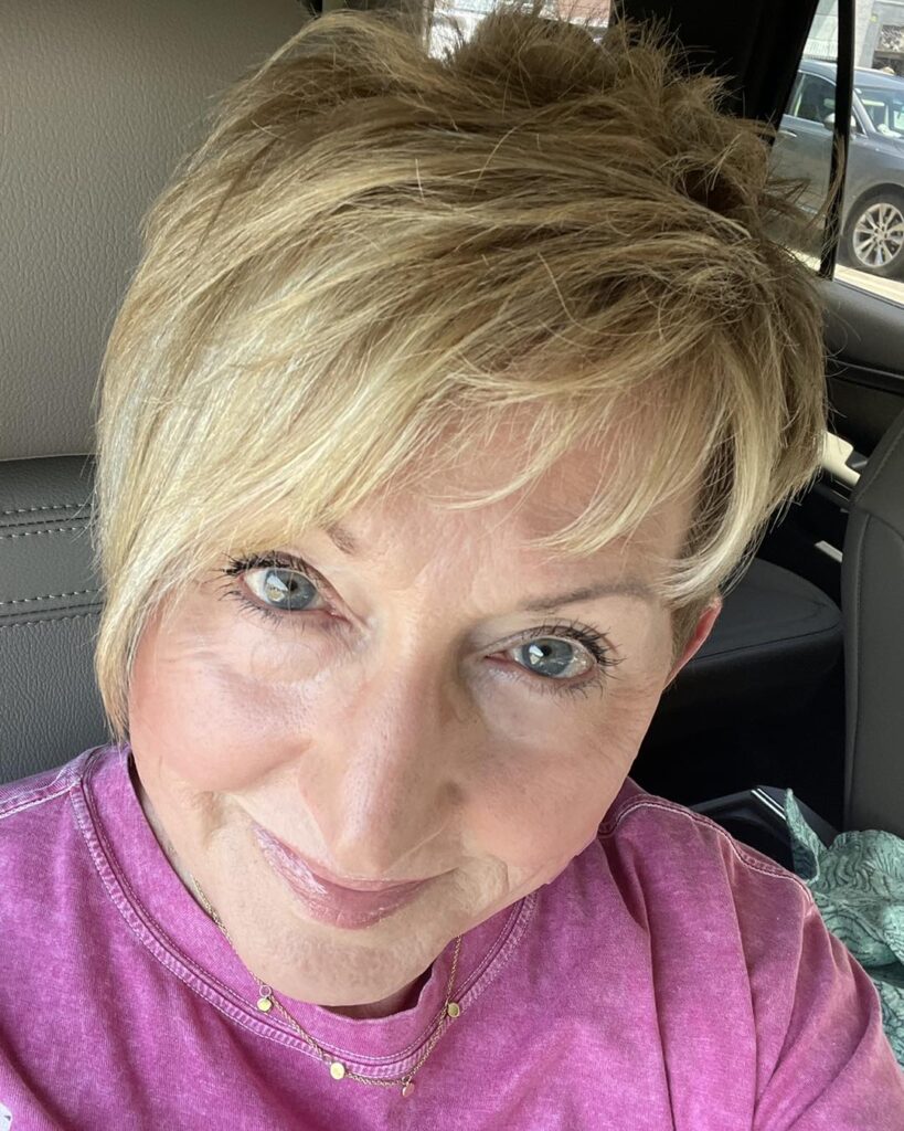 Short blonde layered haircut with volume and soft side swept bangs.