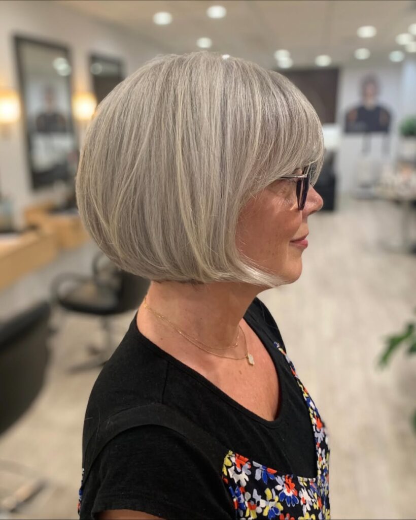 Chin-length blonde bob with a sleek finish and full soft bangs.
